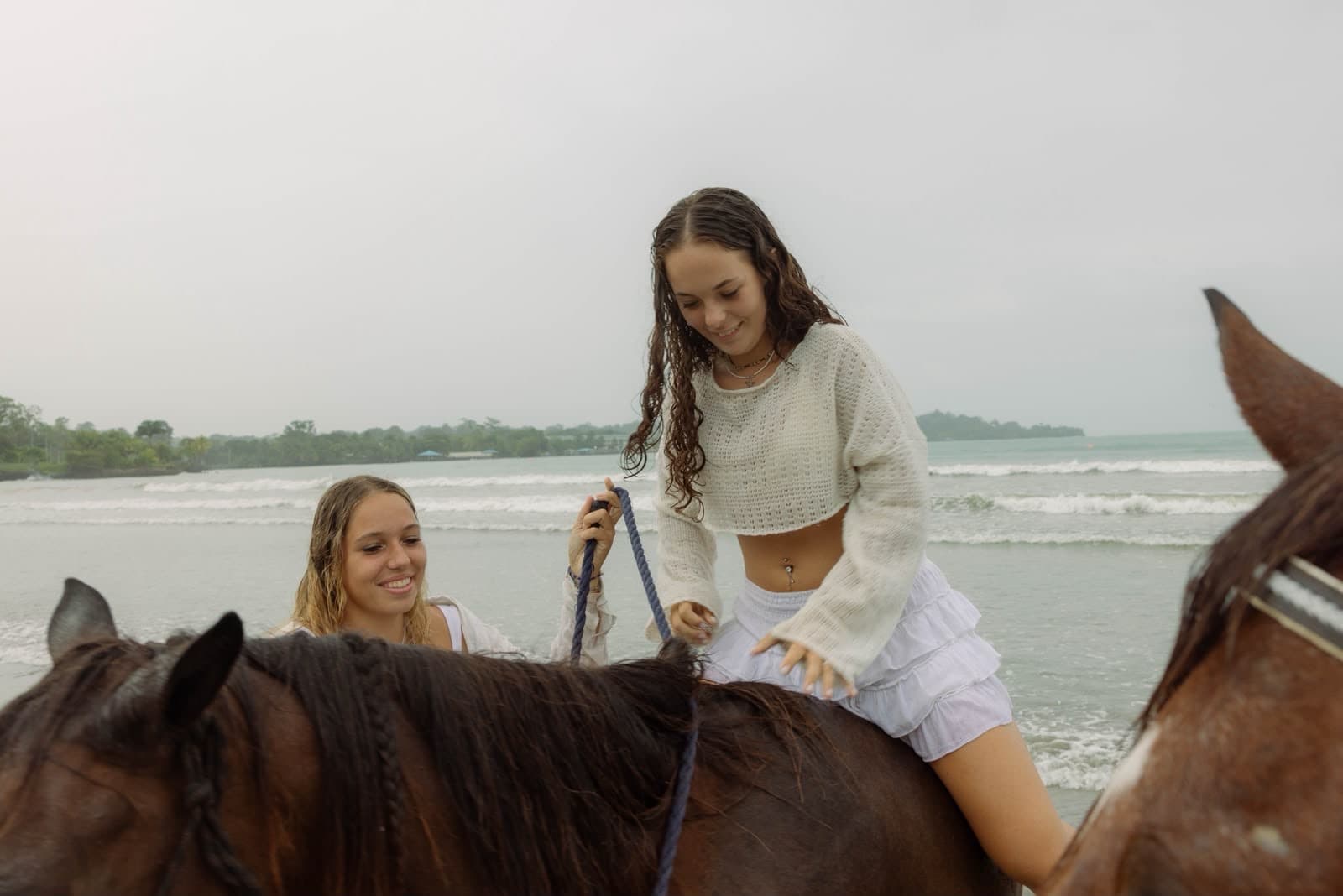 An instructor helping a rider on a calm horse at the beach